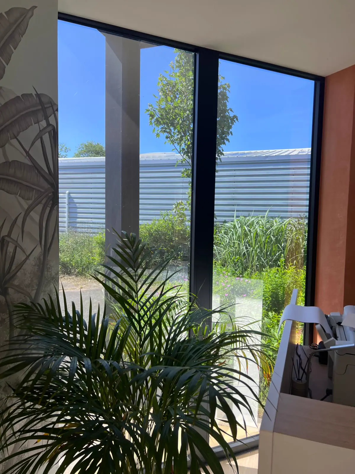 Grande baie vitrée d’un bureau donnant sur un jardin