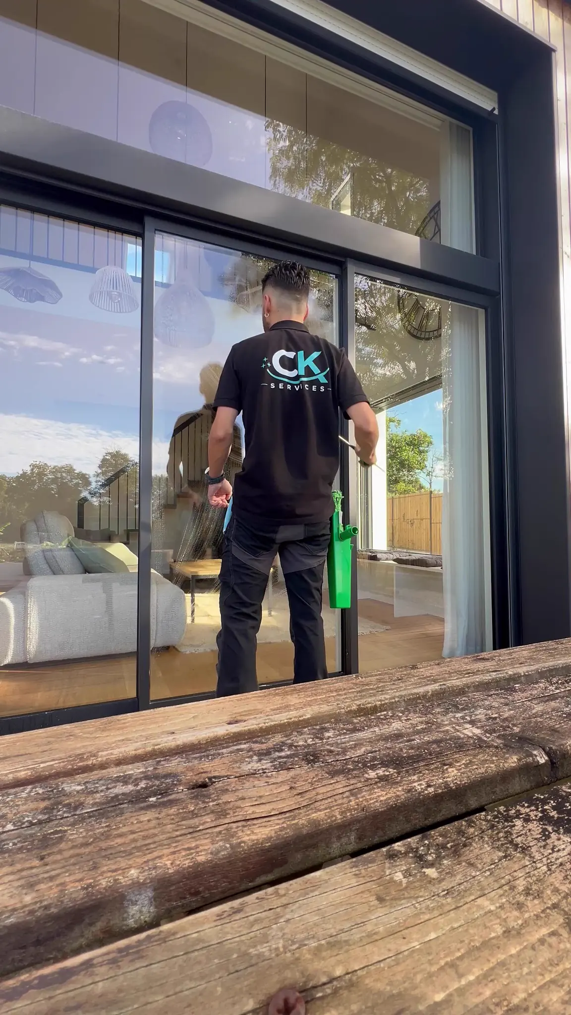 Cyrille, de CK Services, nettoie une grande baie vitrée chez un particulier